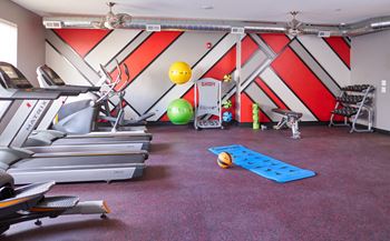 A gym with treadmills and other exercise equipment in a room with a wall